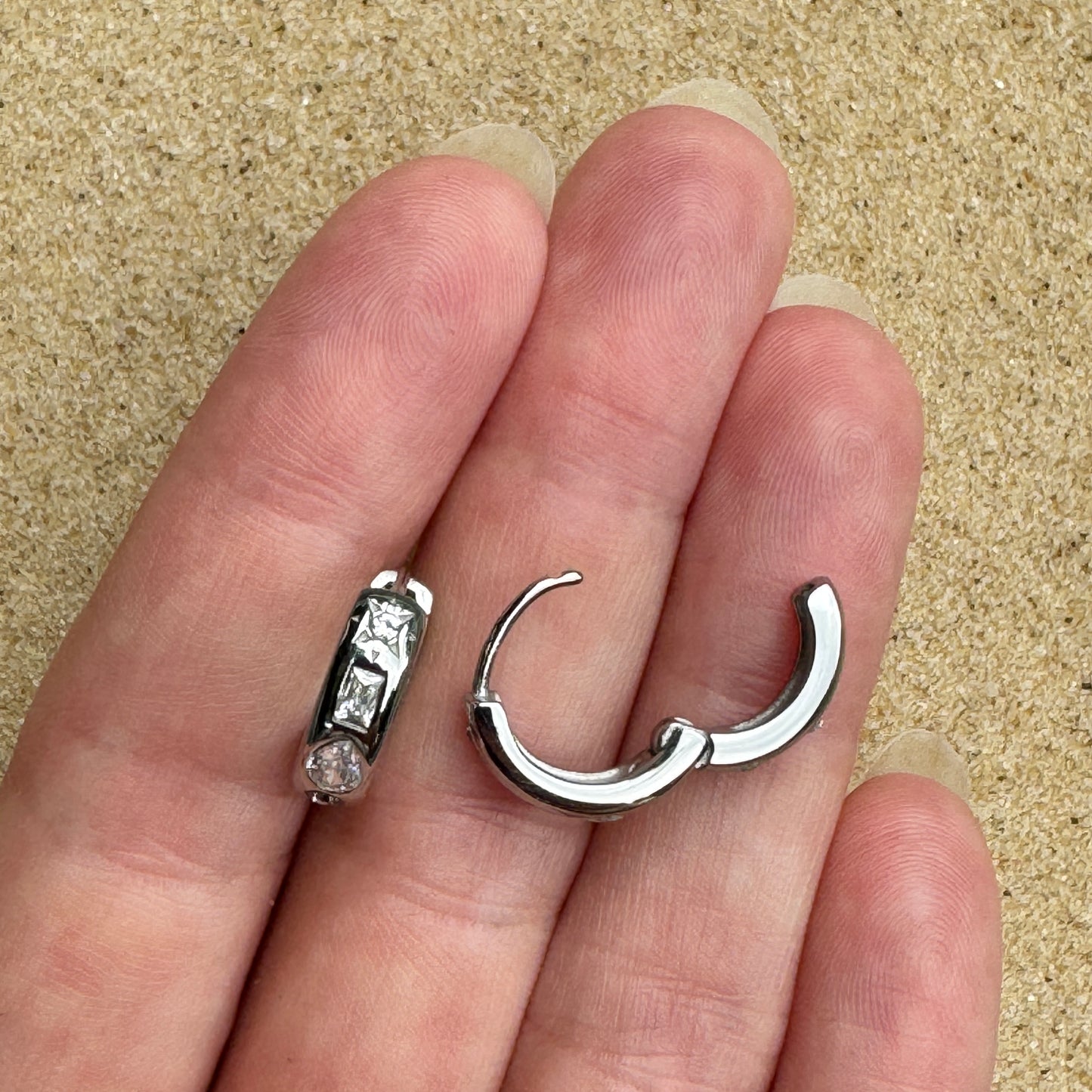 Mixed gem huggie earring in silver in hand