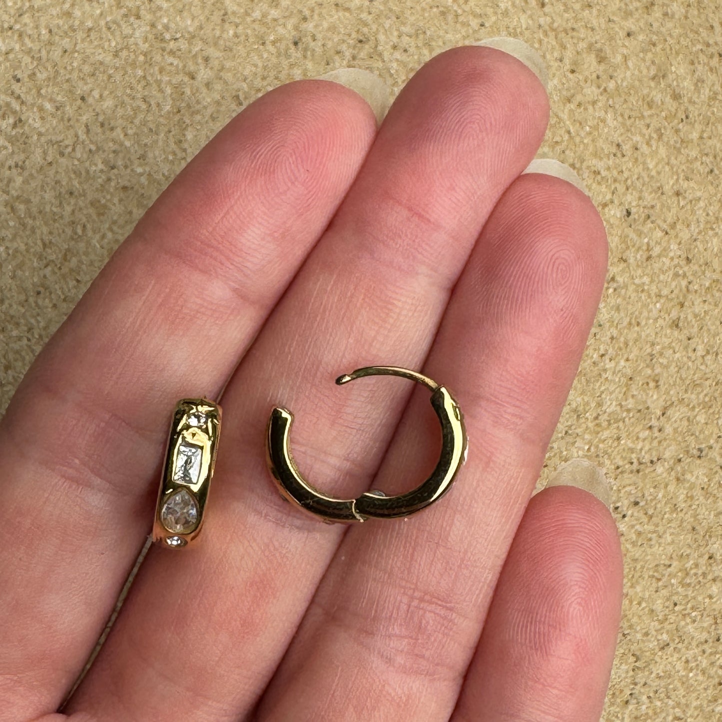 Mixed gem huggie earring in gold in hand