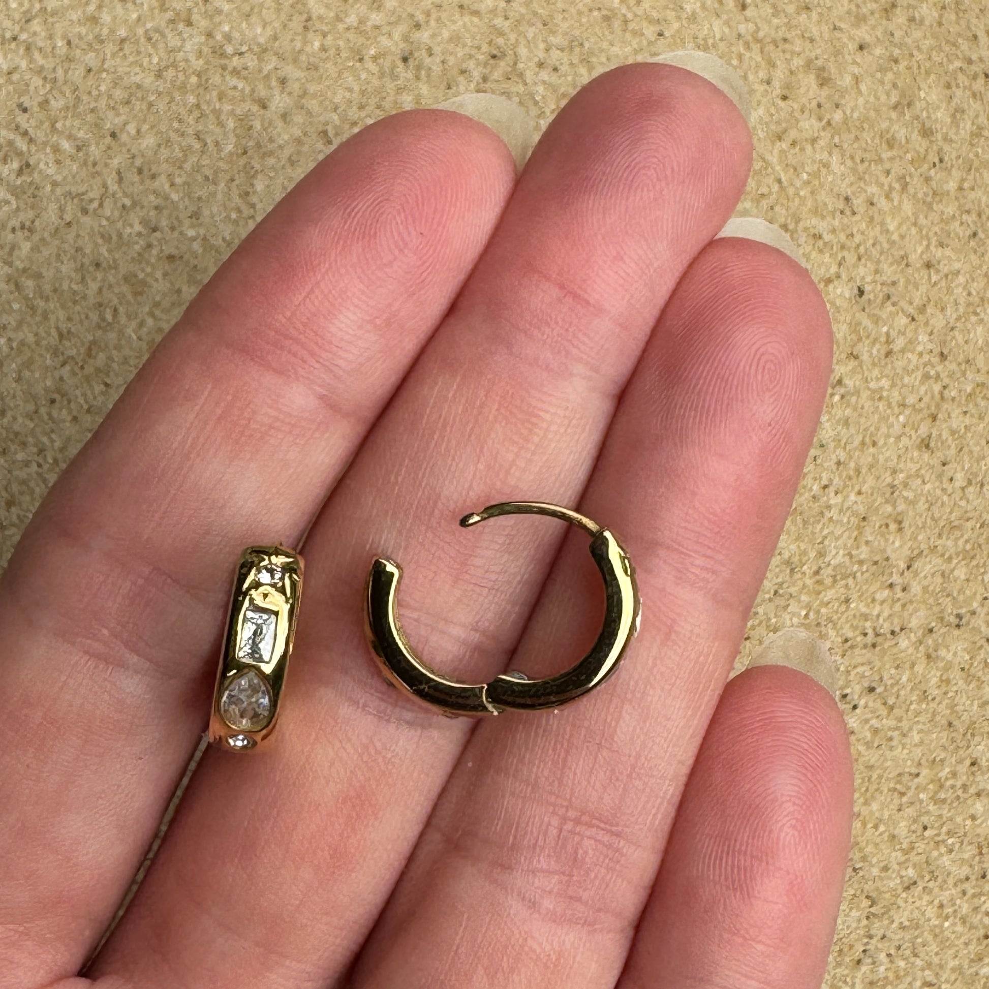 Mixed gem huggie earring in gold in hand