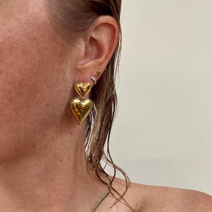 Double Heart Dangly Earrings in Gold, worn on ear.
