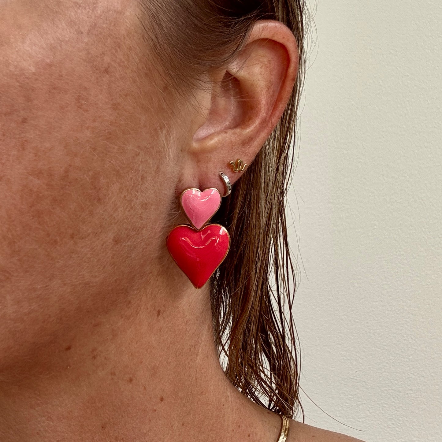 Pink double heart dangly earrings, gold plated studs from Jessica Rose jewellery worn on ear