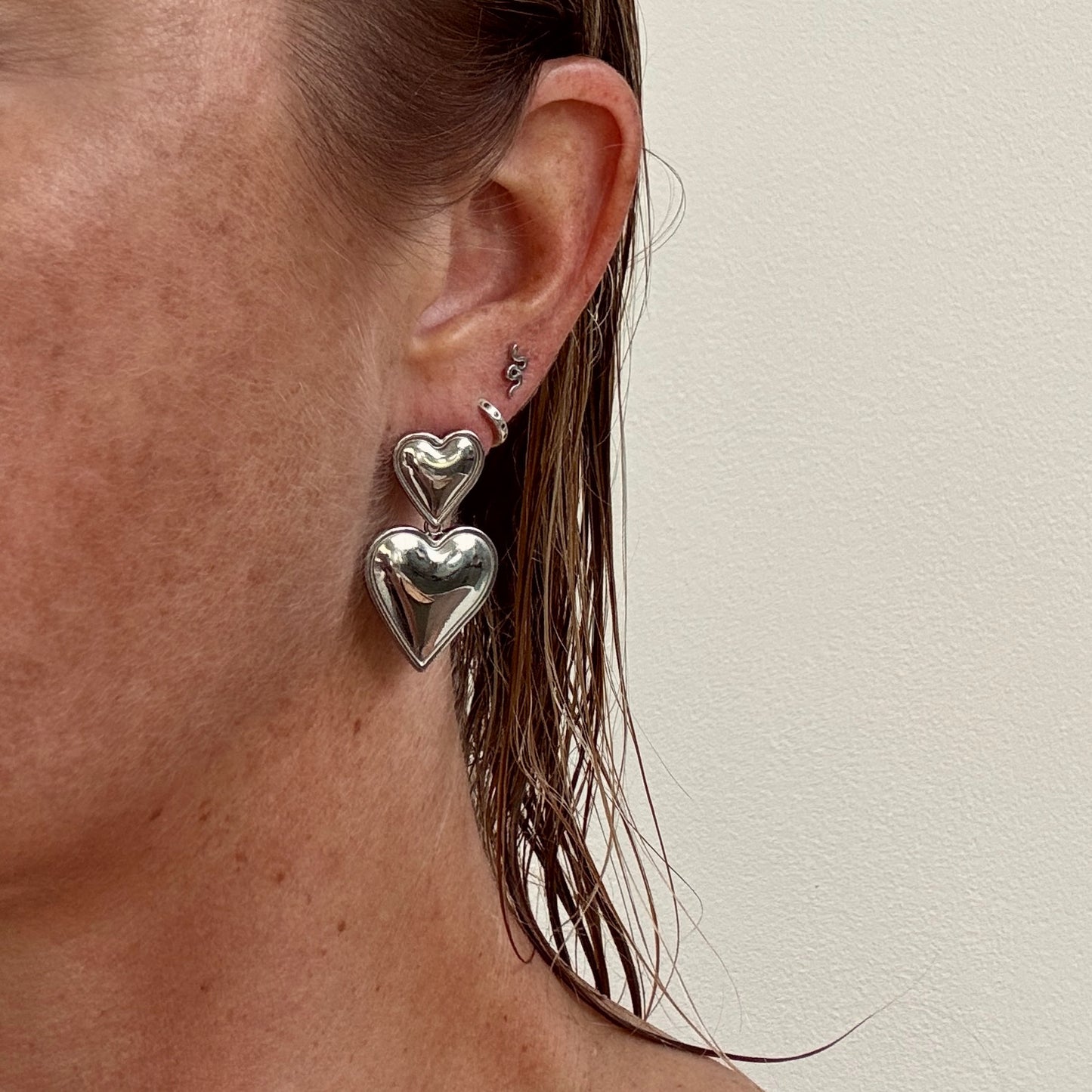 Double Heart Dangly Earrings in Silver worn on ear from Jessica Rose jewellery