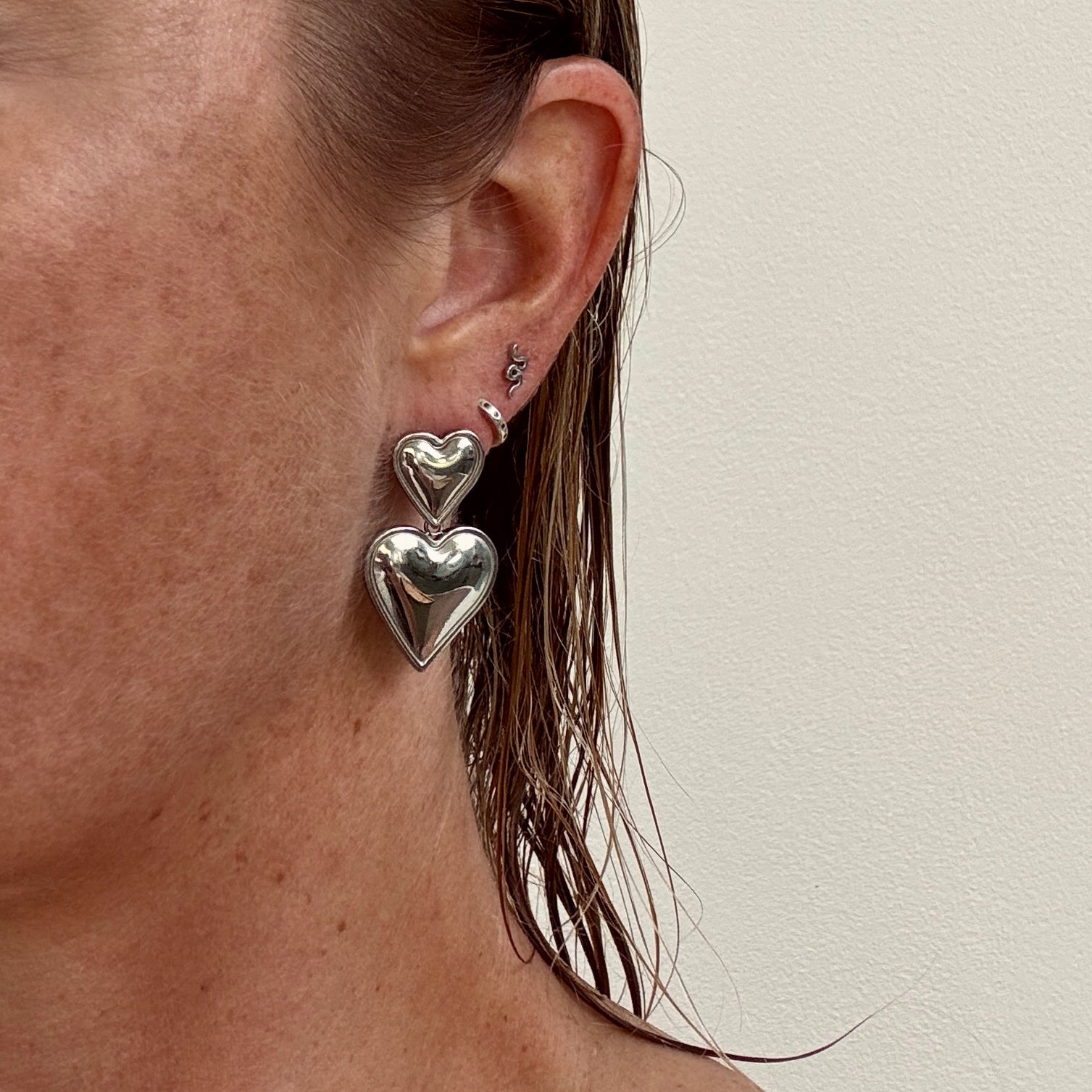 Double Heart Dangly Earrings in Silver worn on ear from Jessica Rose jewellery