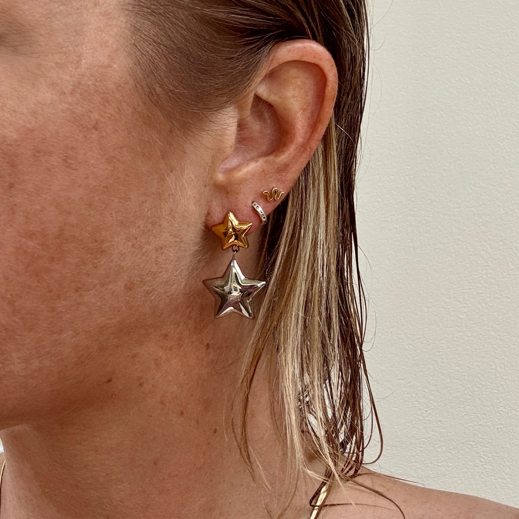 Double Star Dangly Earrings in Silver and Gold worn on ear